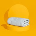 The Slumber Cloud Essential Mattress Pad made with Outlast temperature regulation technology, folded and propped on a yellow background